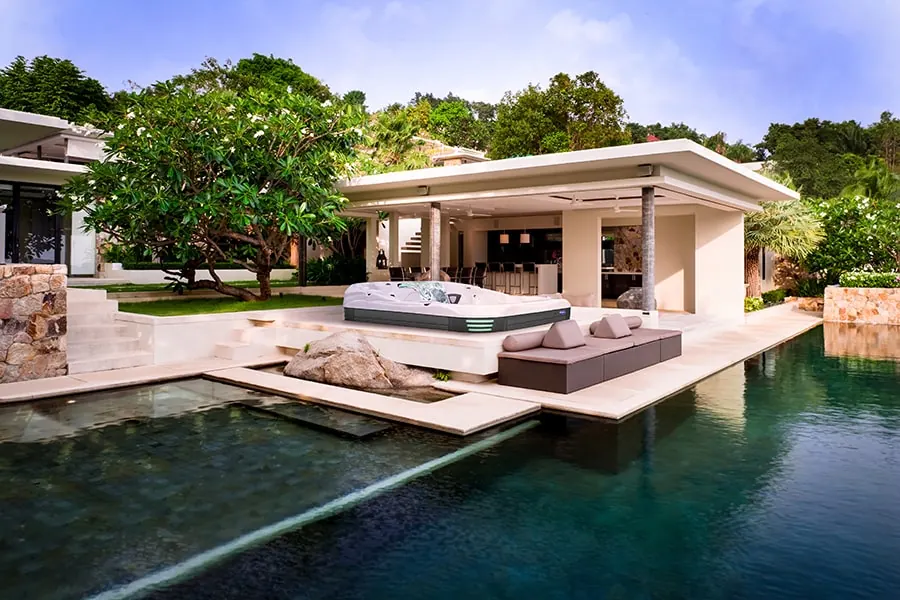 A large hot tub set into a terrace beside a pool at a modern house
